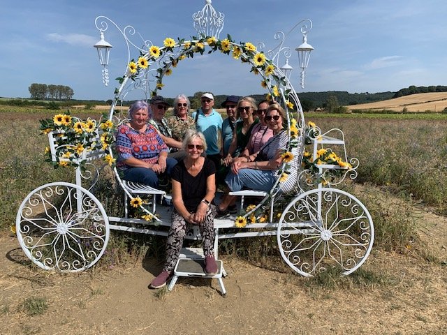 Nature Watch members posing on a carriiage adorned with Sunflowers at Barlow's Sunflower Field